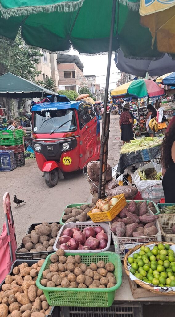Photo of a mototaxi making its way through an open-air market market